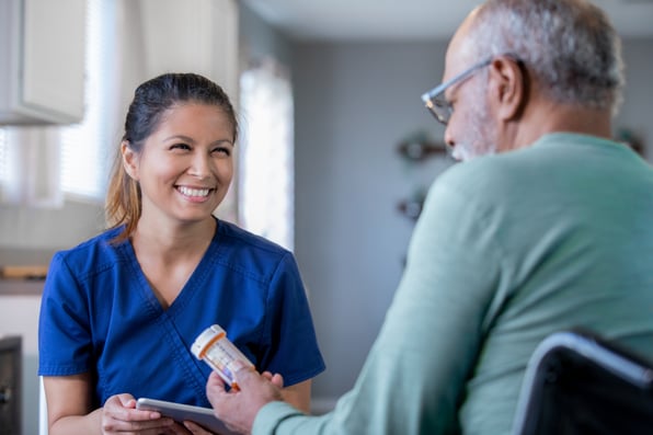 Man receiving care reading a prescription bottle