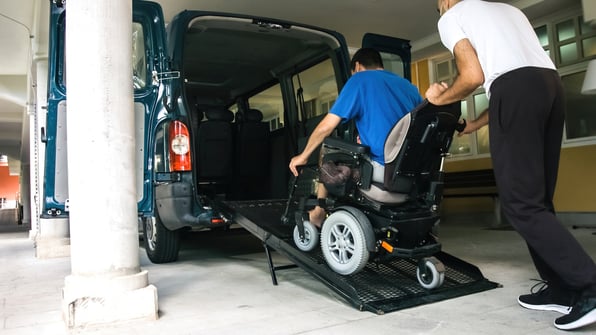 person being pushed into a van in a wheelchair